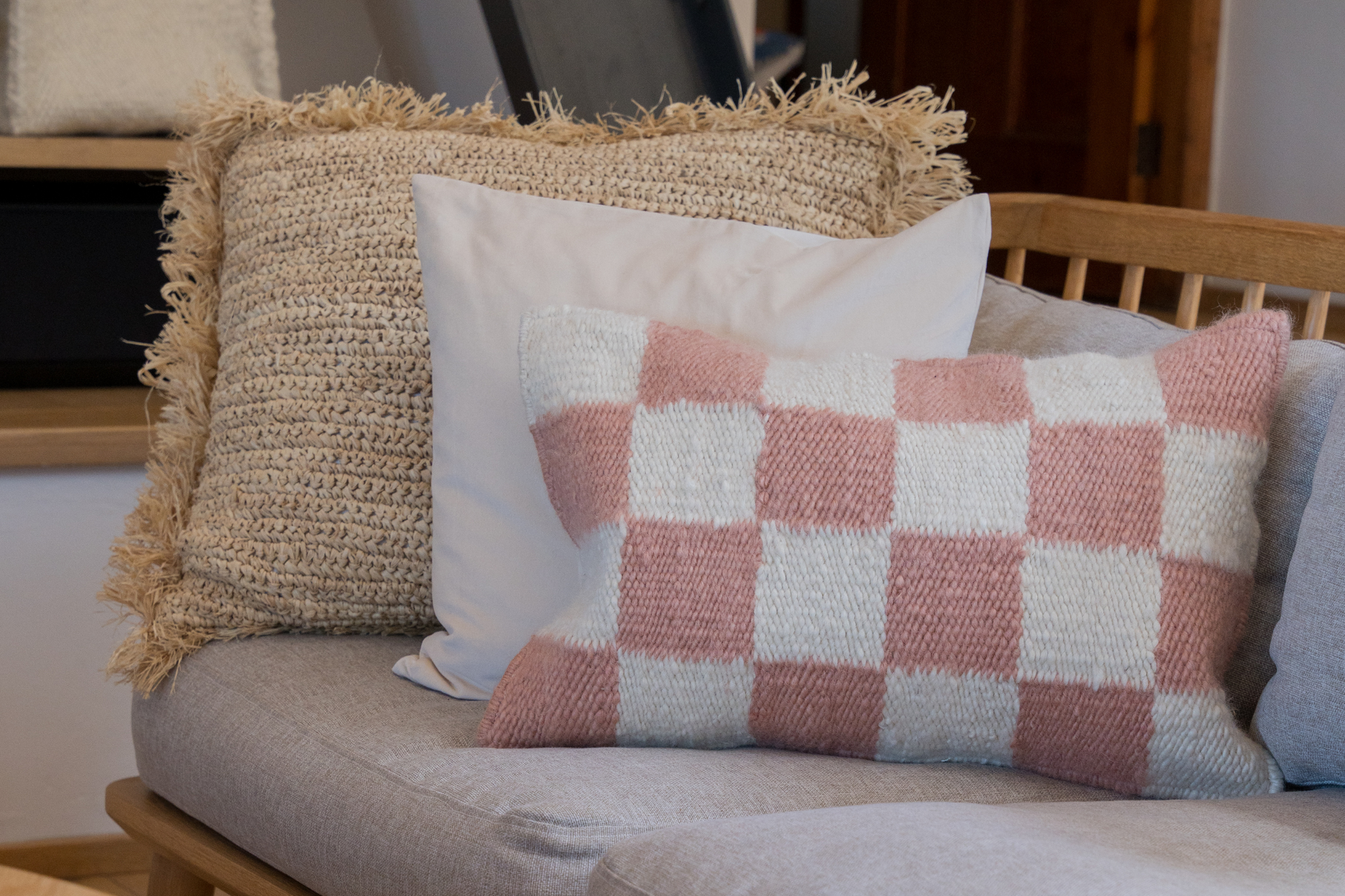 Decorative pillows on a sofa featuring the Raffia cushion cover, and woven scatter cushions from Coral & Hive 