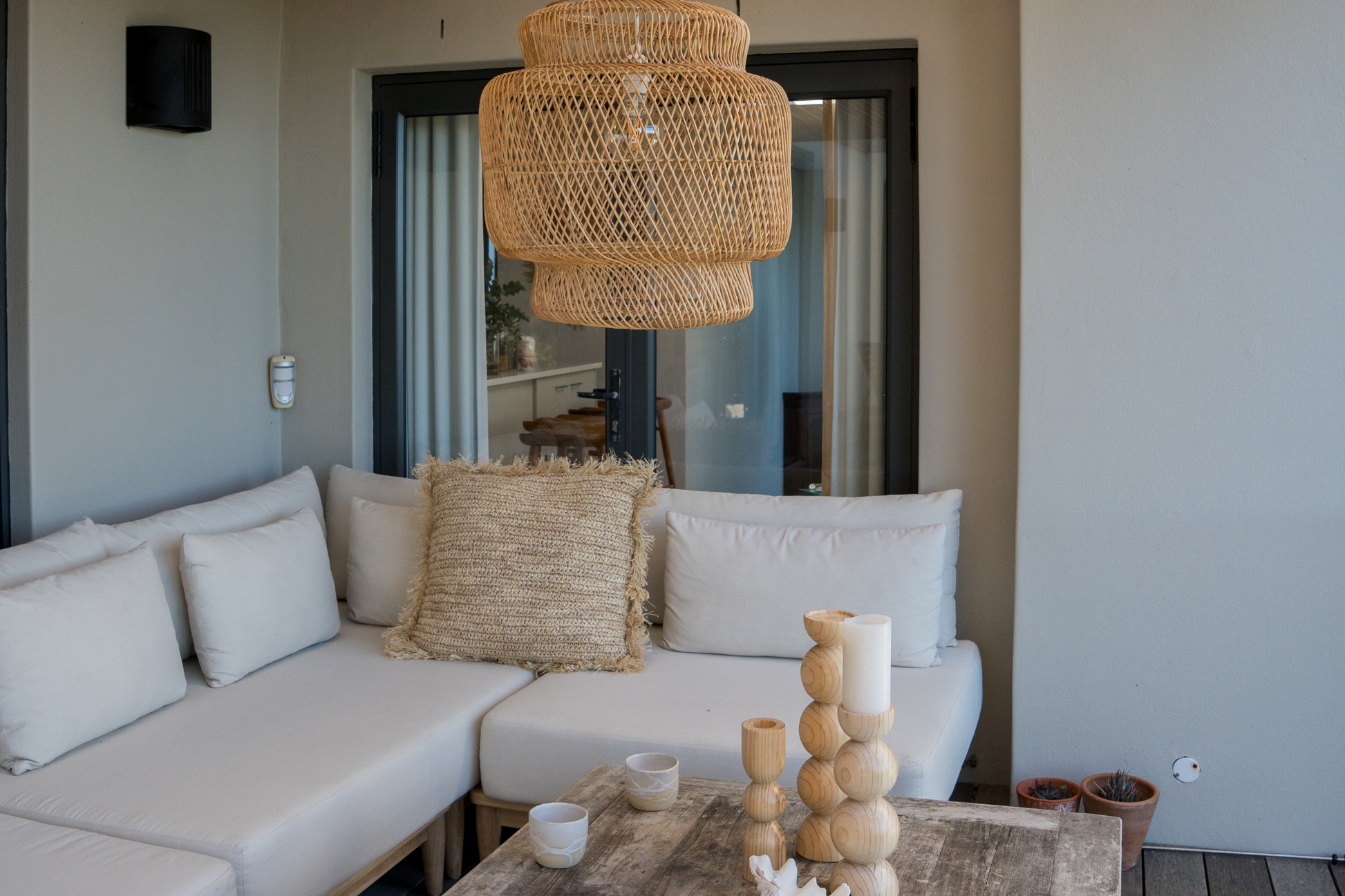 Open plan outdoor living room with a wicker chandelier, and decorative items that are robust and great for porches and gardens