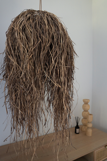 Textured pendant light fixture hanging in a room with wooden ceiling and window.
crates_of_beauty_woven_hanging_raffia_dome_pendant