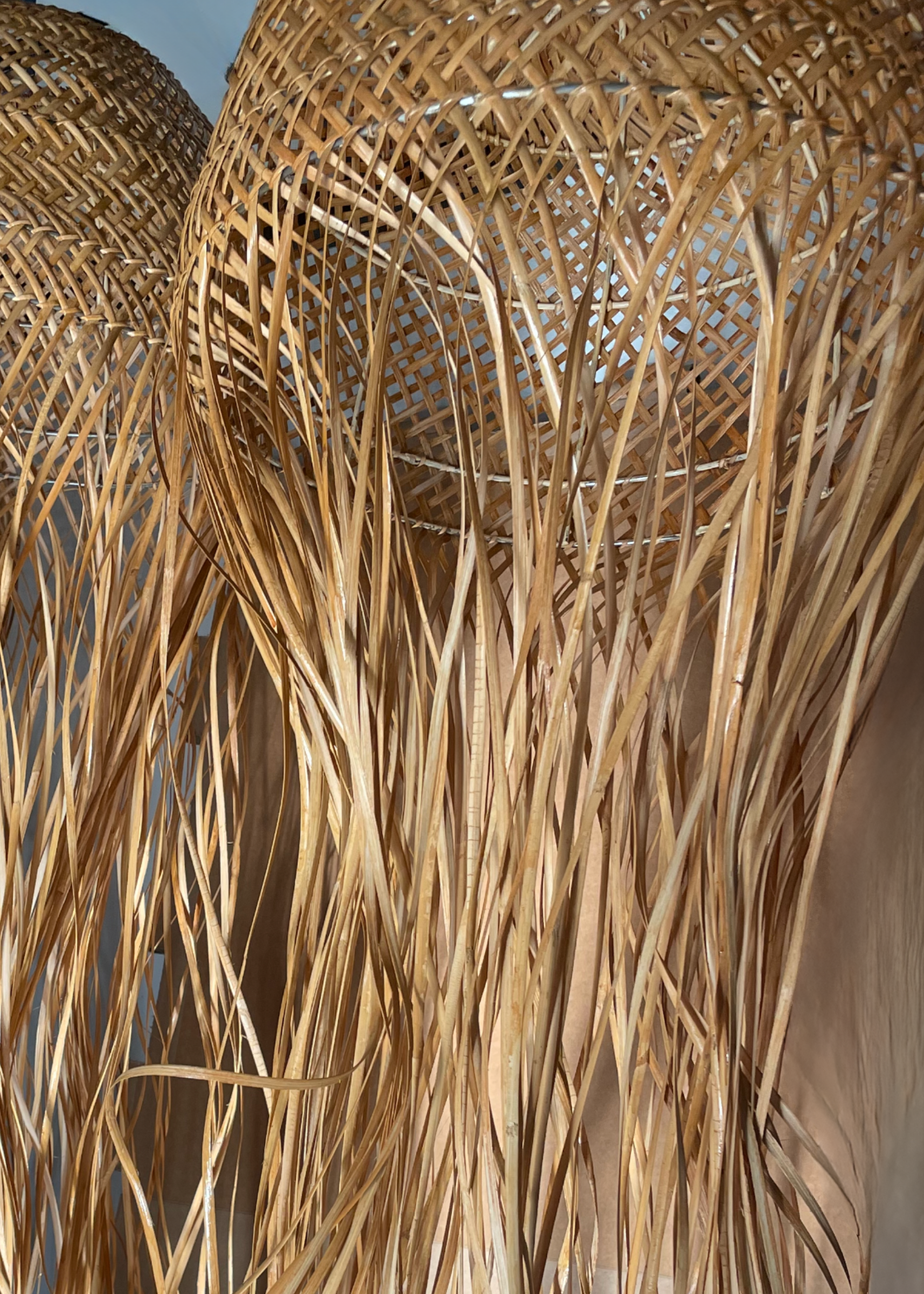 Two wide woven jellyfish shades on display with dome frame, wide weave, and long tentacles in rattan