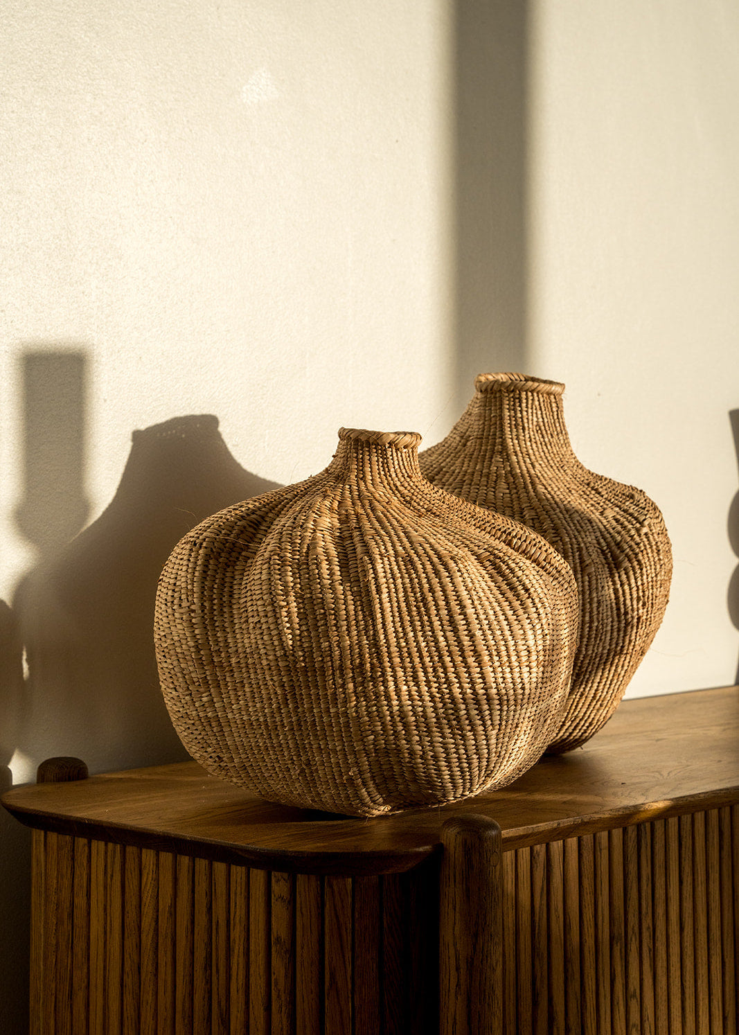 Two garlic gourds photographed on a side table with afternoon sun on them