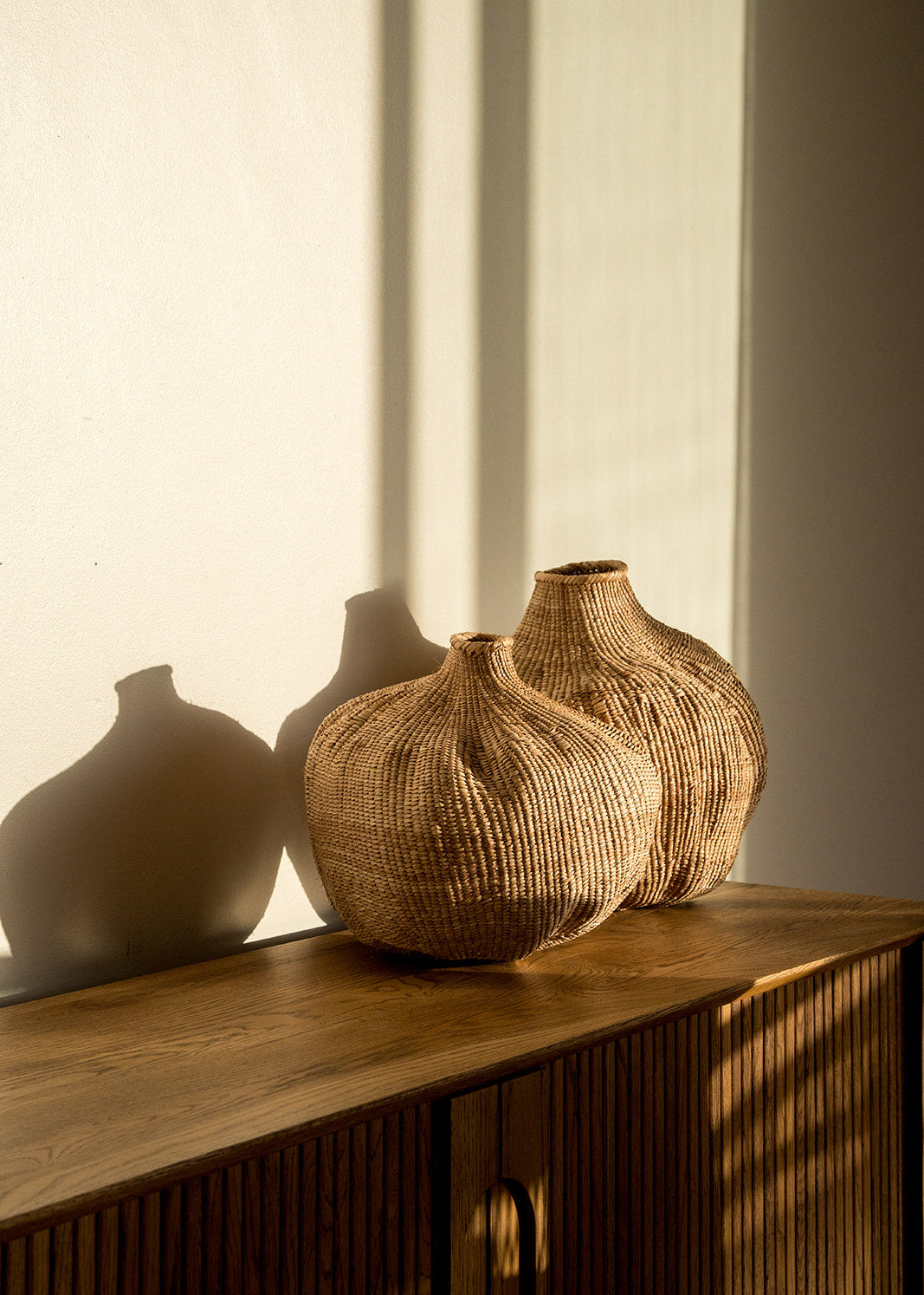 Two of the garlic gourds photographed on a side table with afternoon sun on them