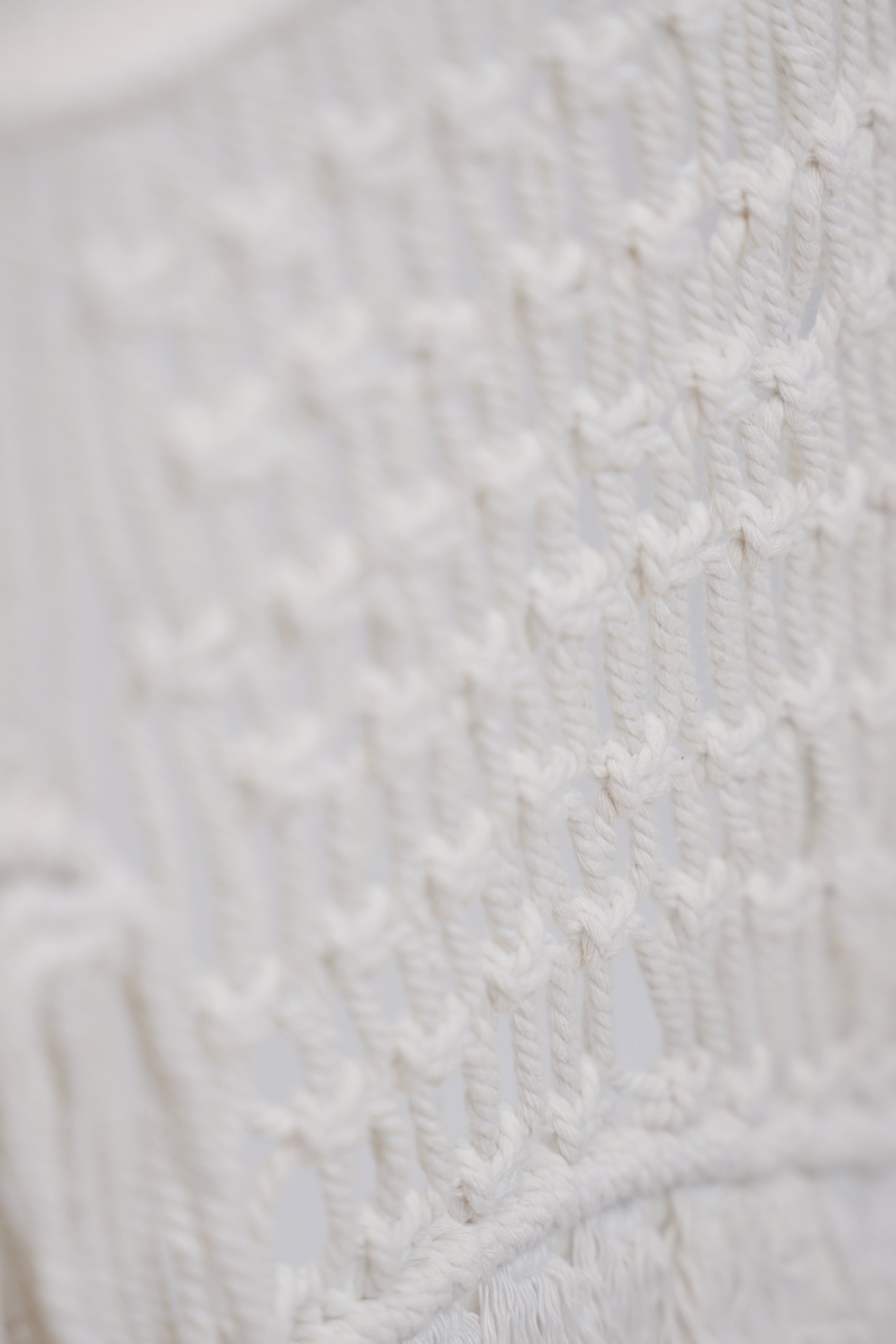 The Macrame wall hanger hand woven with crisp white macrame on a one of a kind wooden rod