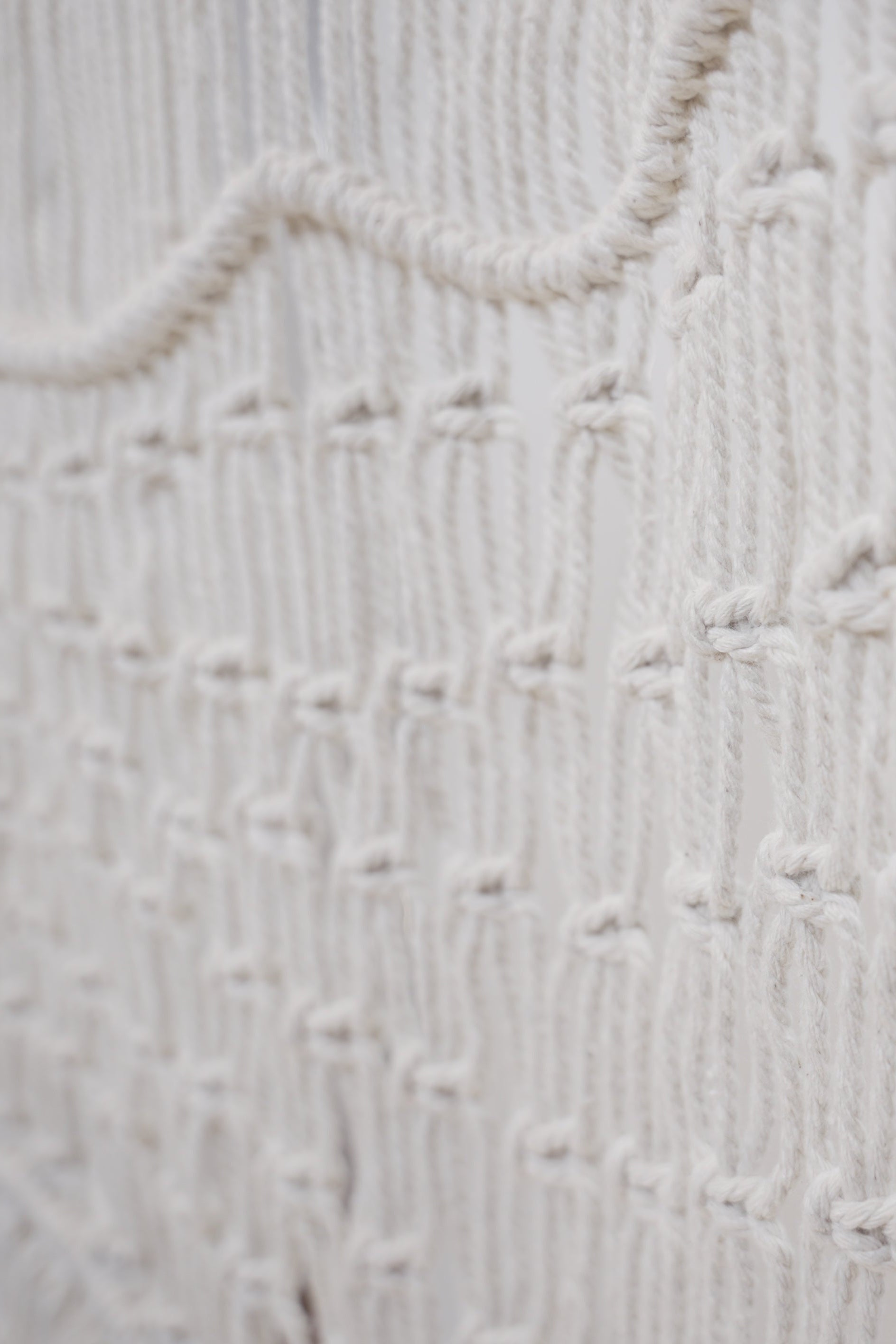 The Macrame wall hanger hand woven with crisp white macrame on a one of a kind wooden rod