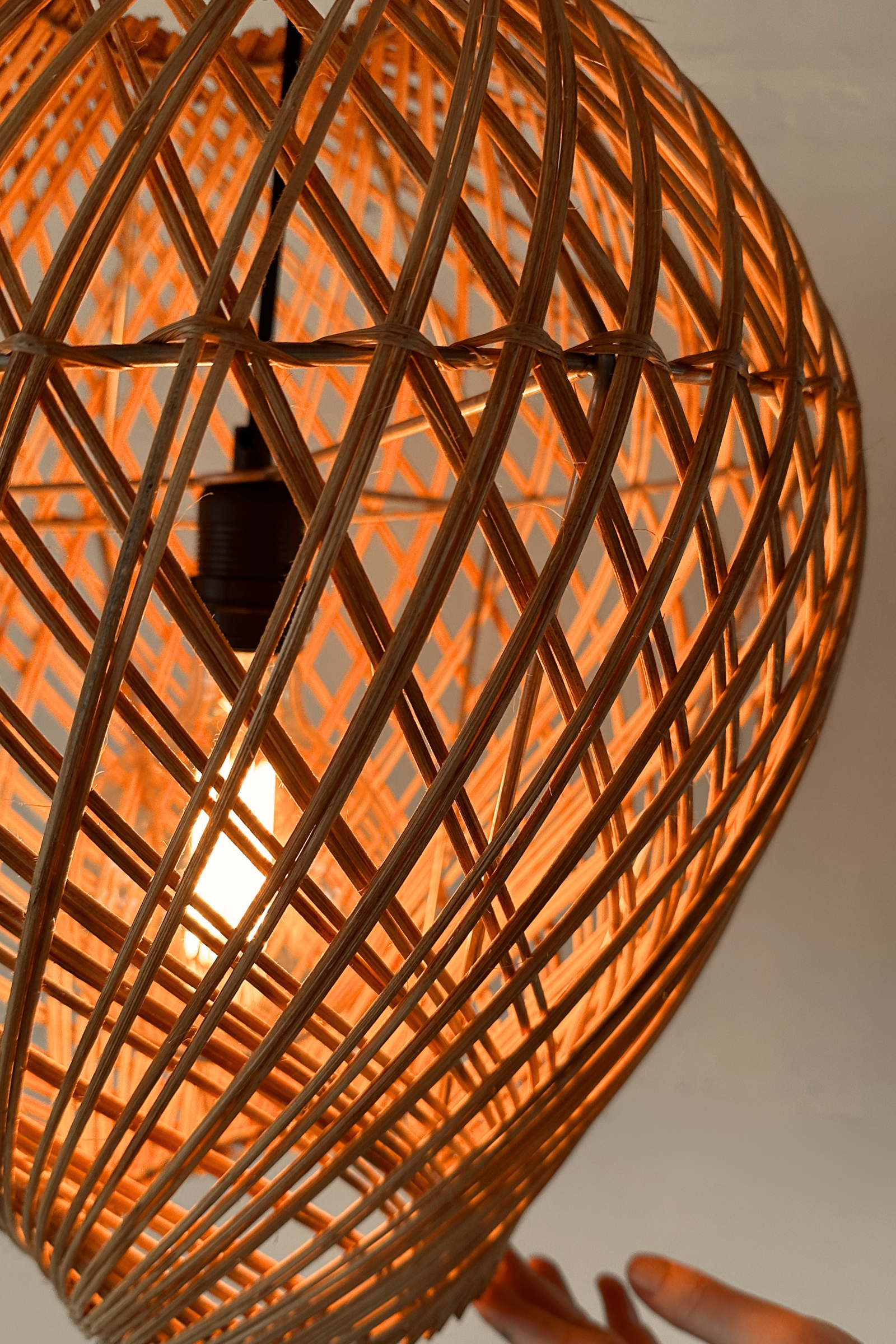 Locally handwoven rattan pendant light with a warm glow up close