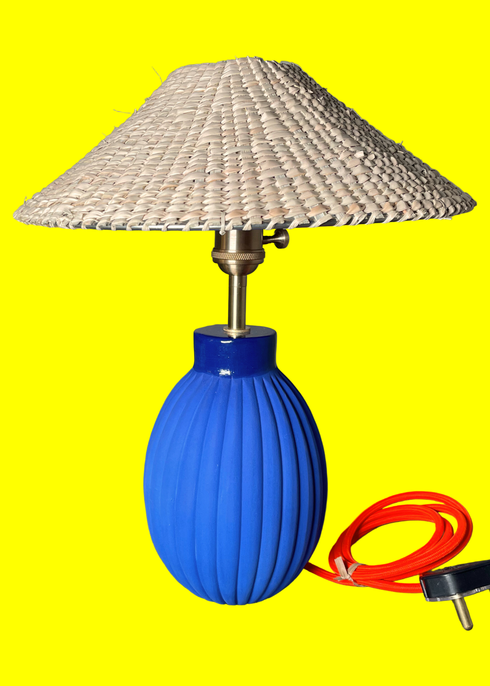 Table lamp with blue base and wavy design, featuring a woven shade on a yellow background.