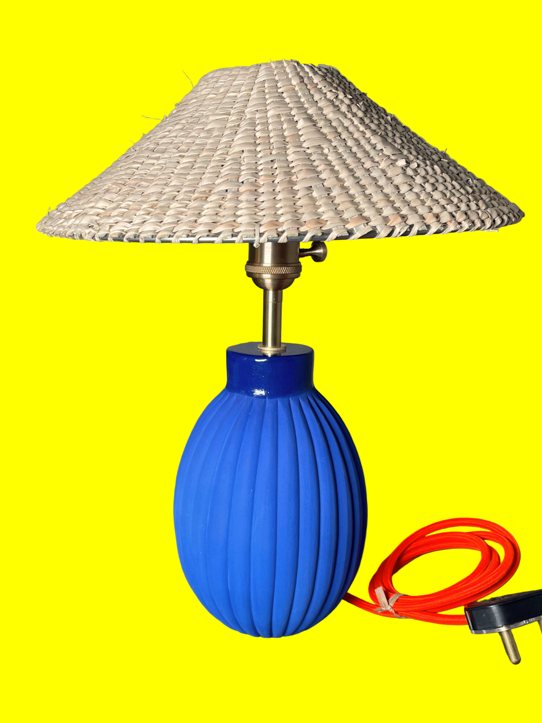 Table lamp with blue base and wavy design, featuring a woven shade on a yellow background.