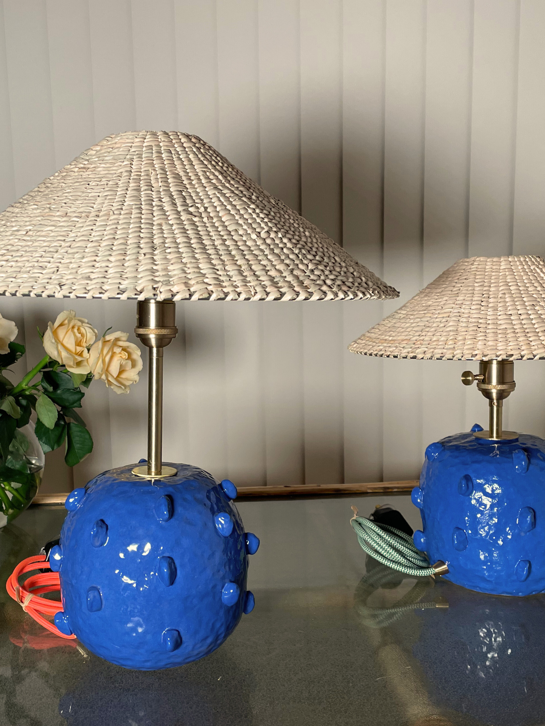 Two table lamps with blue ceramic bases and wicker shades with brass fittings
