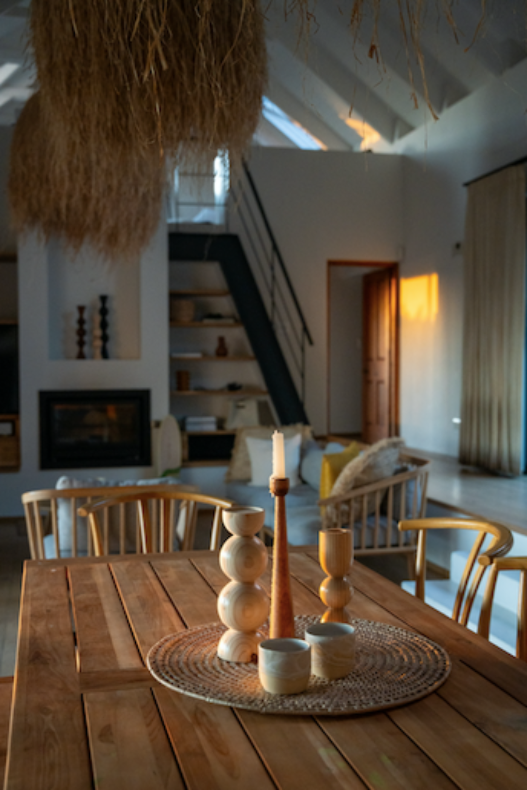 Dining area with wooden candle holders, woven placemat, grass lampshade