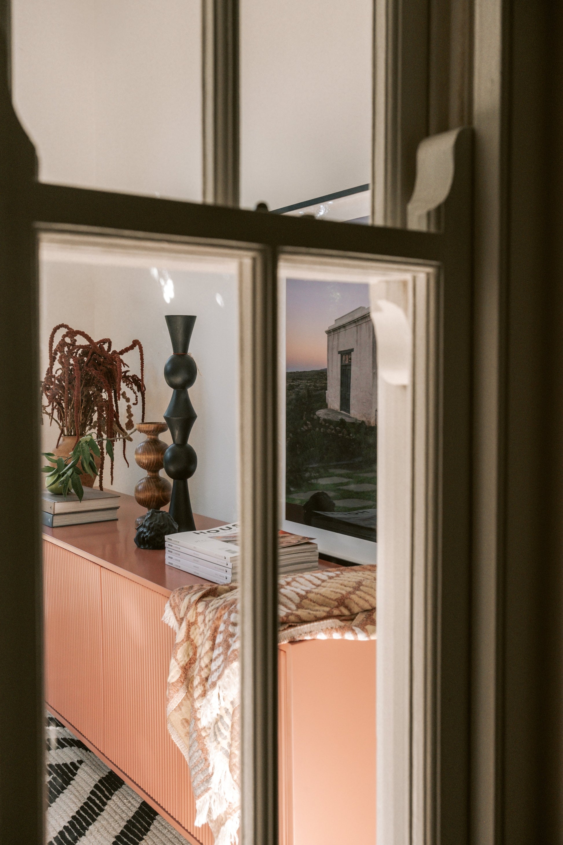 View through a window into a bedroom with wooden home decor for candles