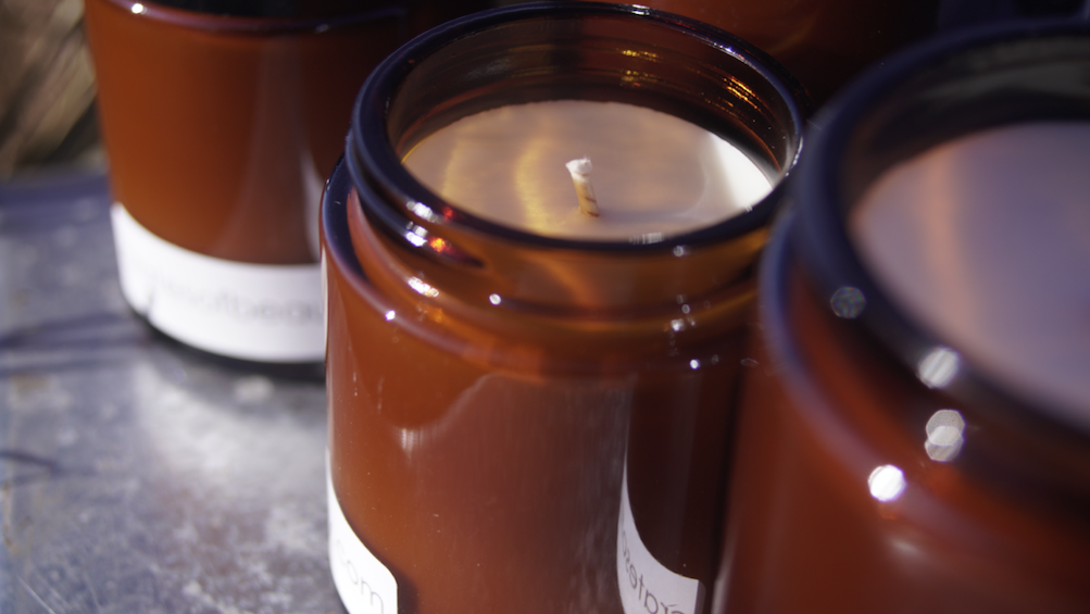 Close-up of soy candles in amber glass jars with cotton wick