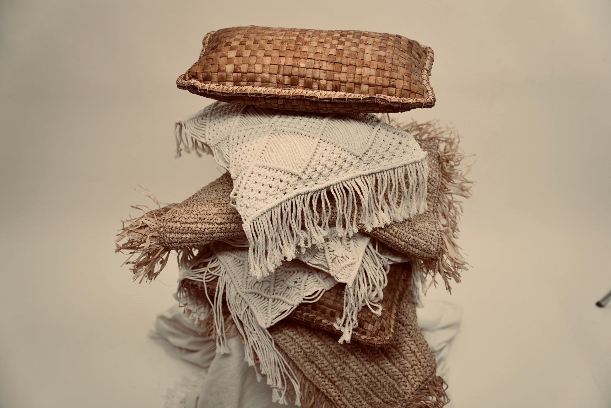 A stacked heap of cushions consisting of the Raffia cushion cover, macrame cushion covers, and our crispy woven scatter cushions