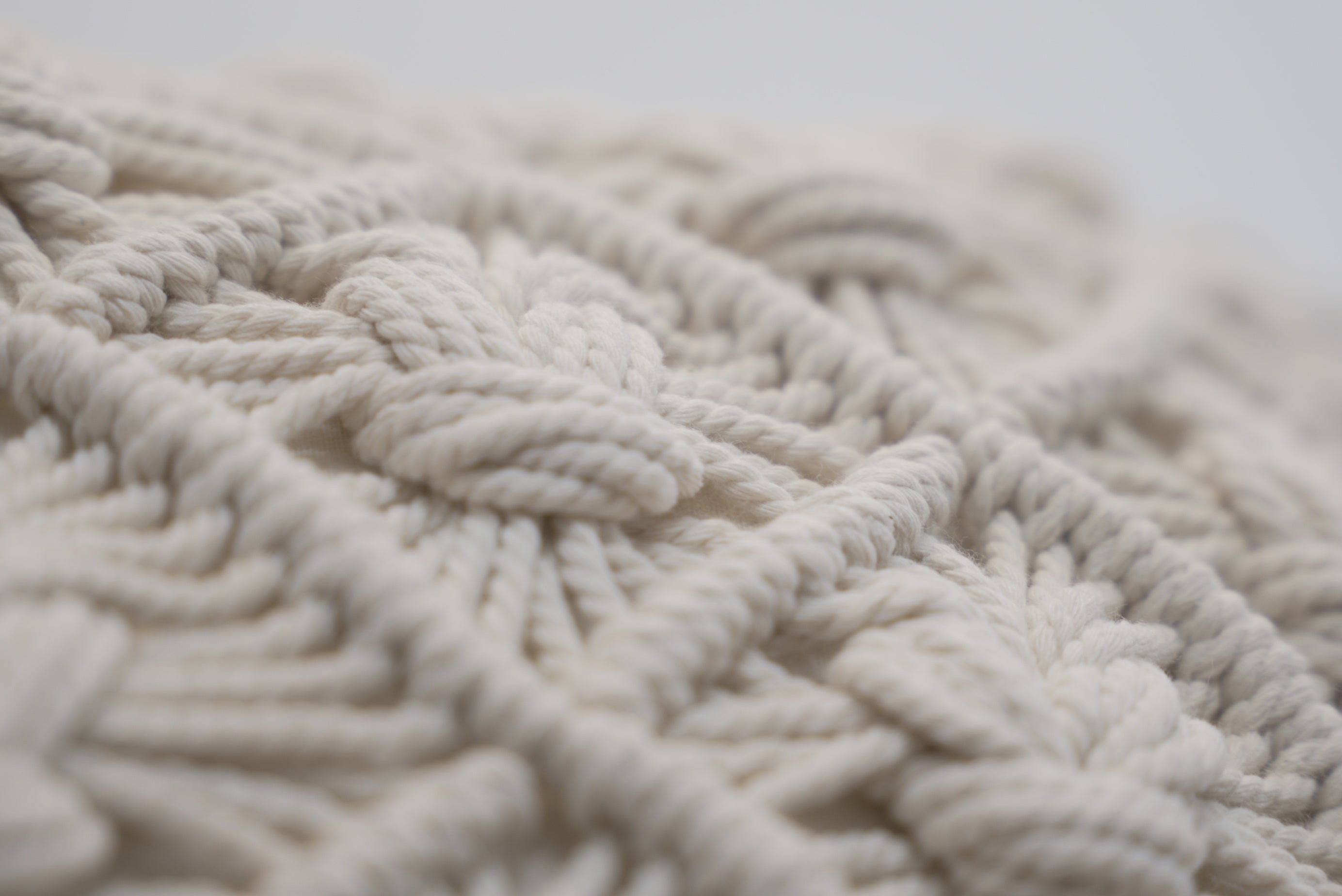 A close-up of the macrame scatter cushion in white with knots