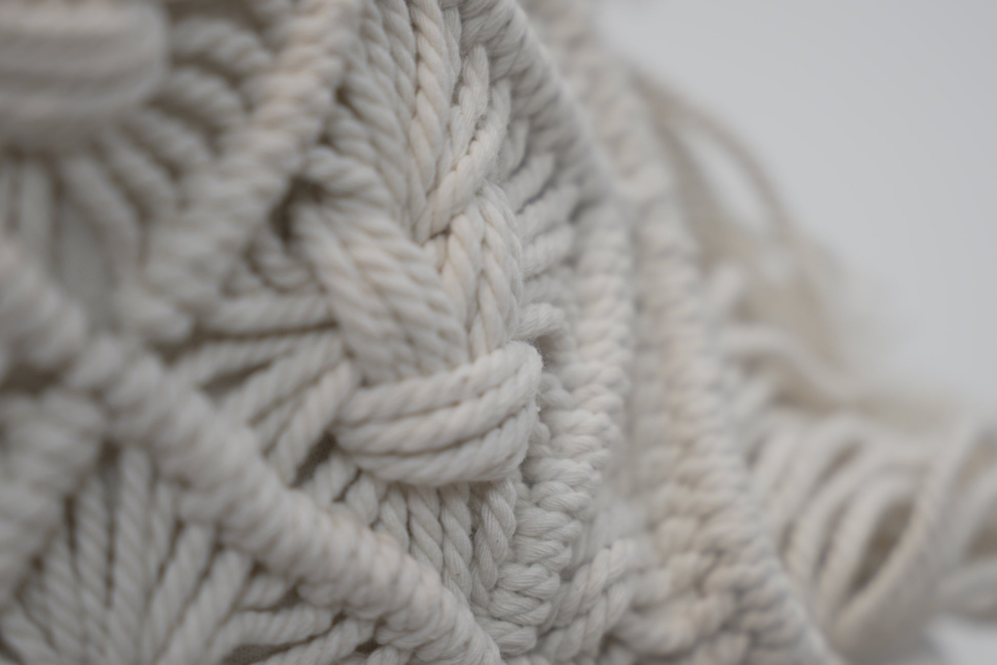 A close-up of the macrame scatter cushion with detail in bright white