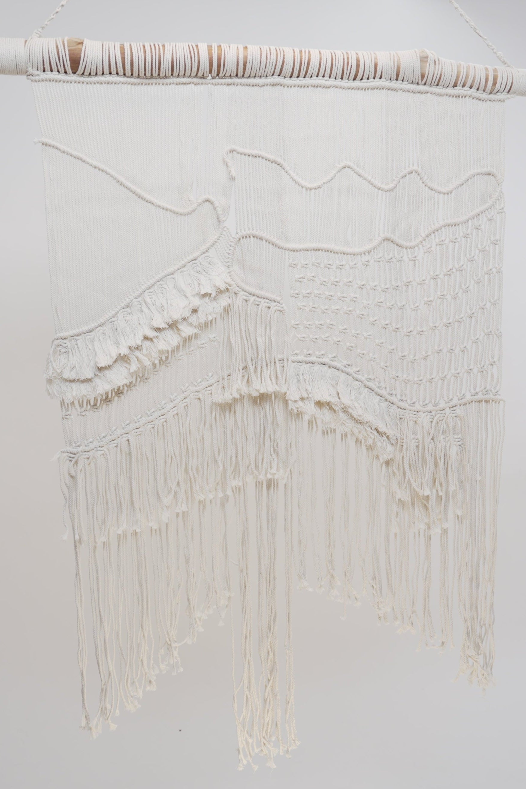 The Macrame wall hanger hand woven with crisp white macrame on a one of a kind wooden rod