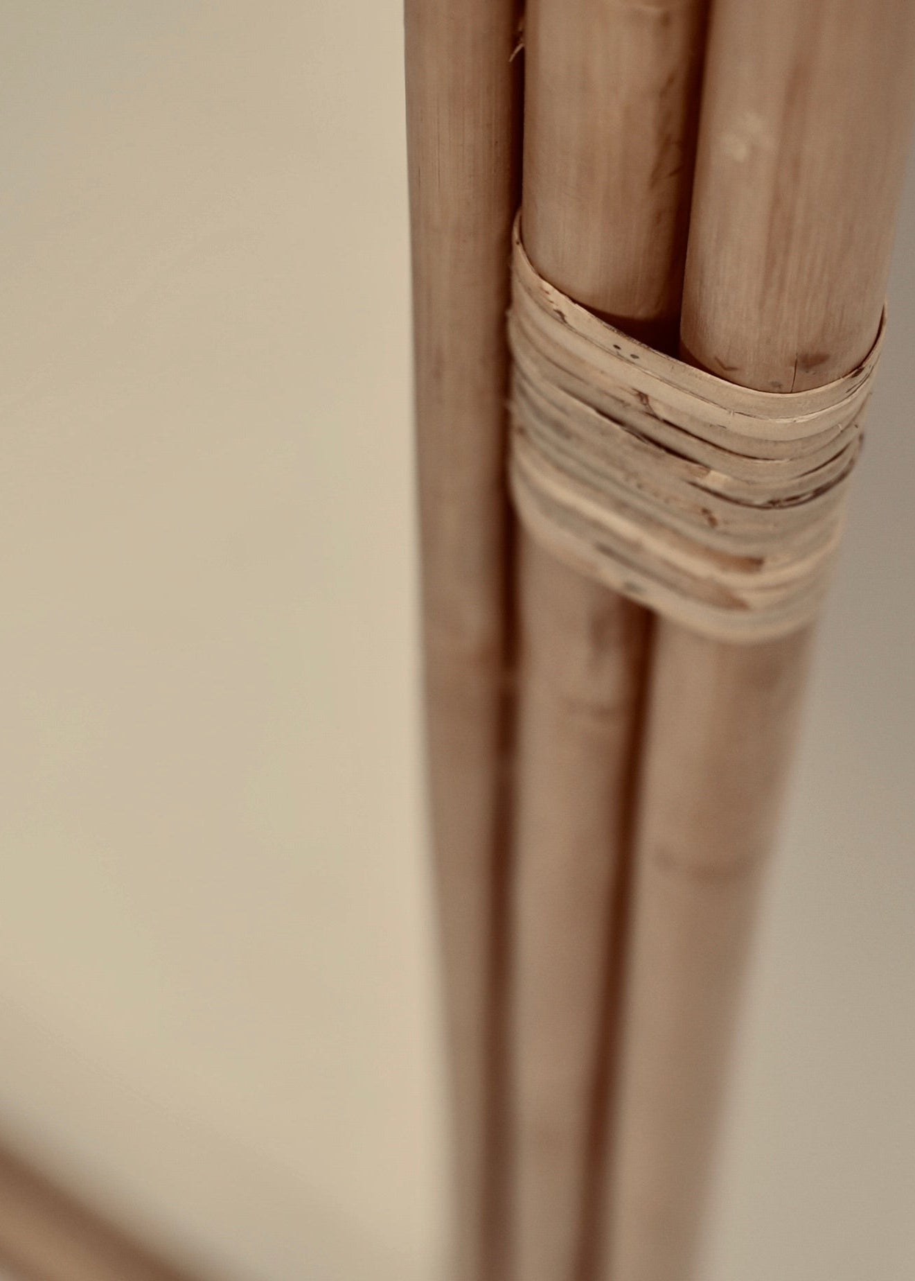 A close-up of the Ibu mirror hand woven from rattan free standing wall mount with hanging rods for towels